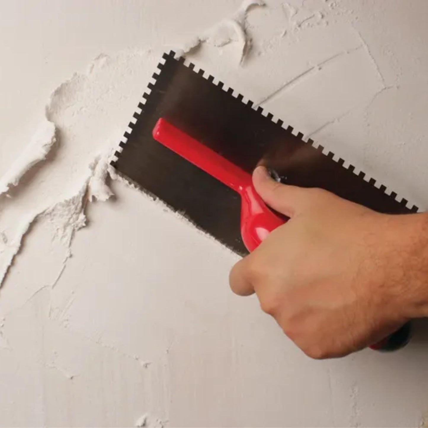 Detalhe da aplicação de argamassa em parede utilizando pente de aço Rubi com cabo aberto.