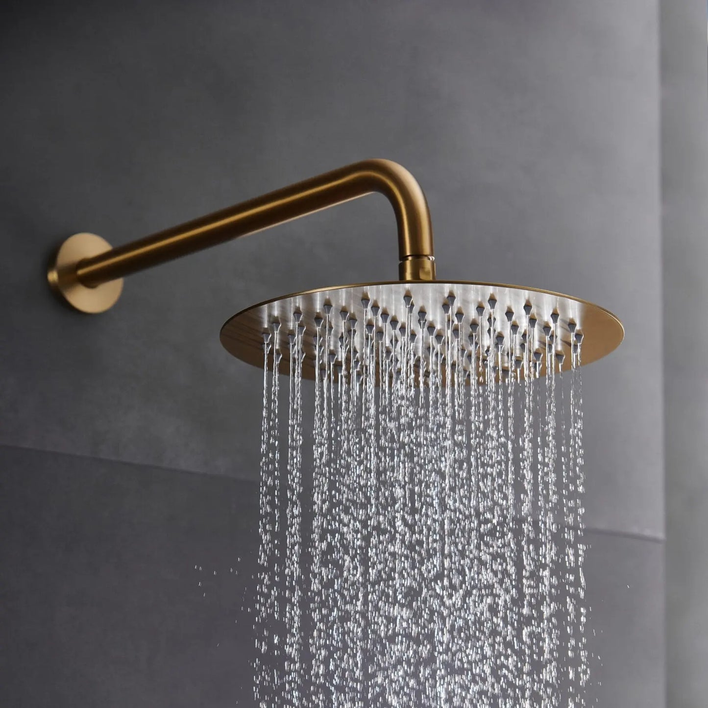 Detalhe do chuveiro de teto extraplano Monza ouro mate em funcionamento com jato de chuva.
