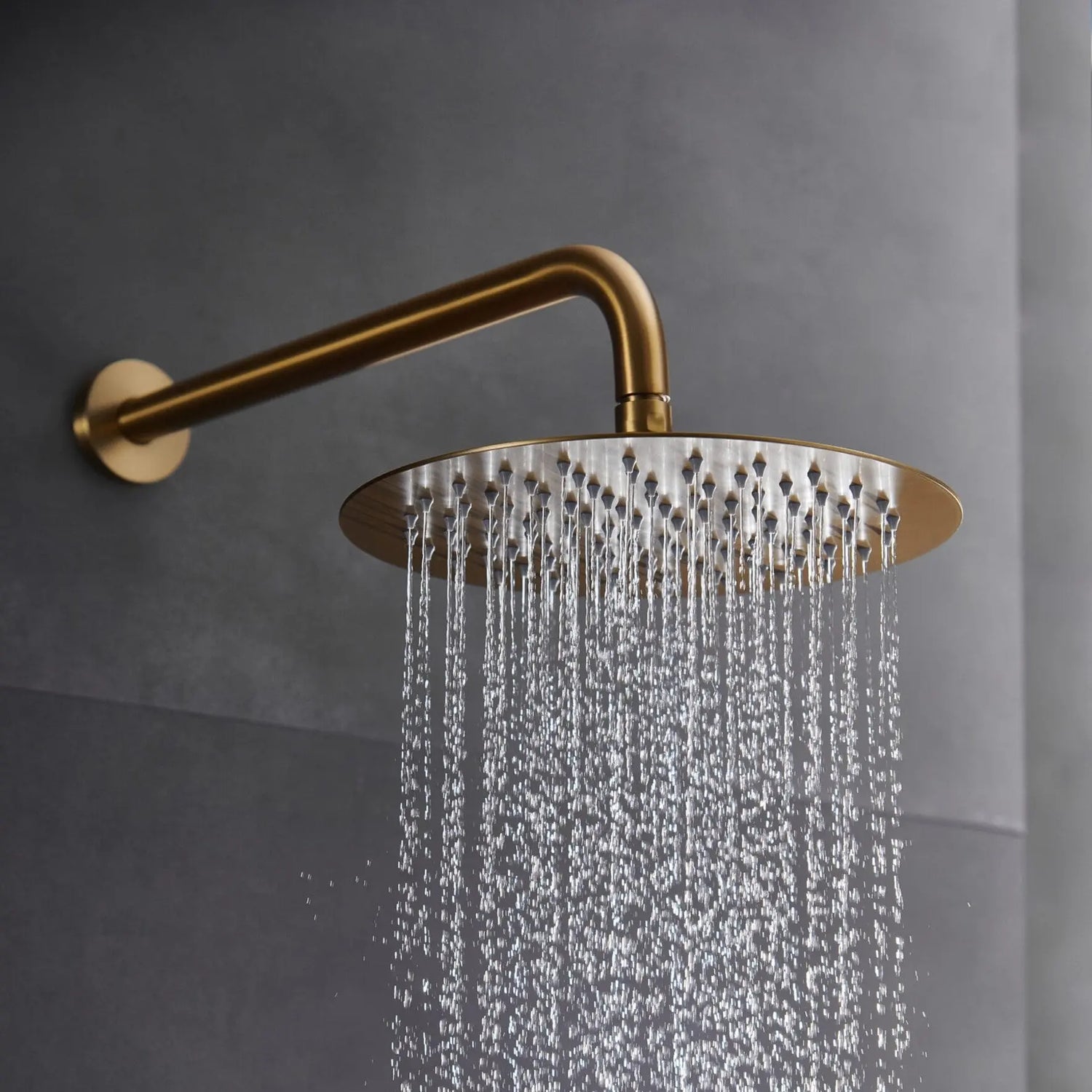 Detalhe do chuveiro de teto extraplano Monza ouro mate em funcionamento com jato de chuva.