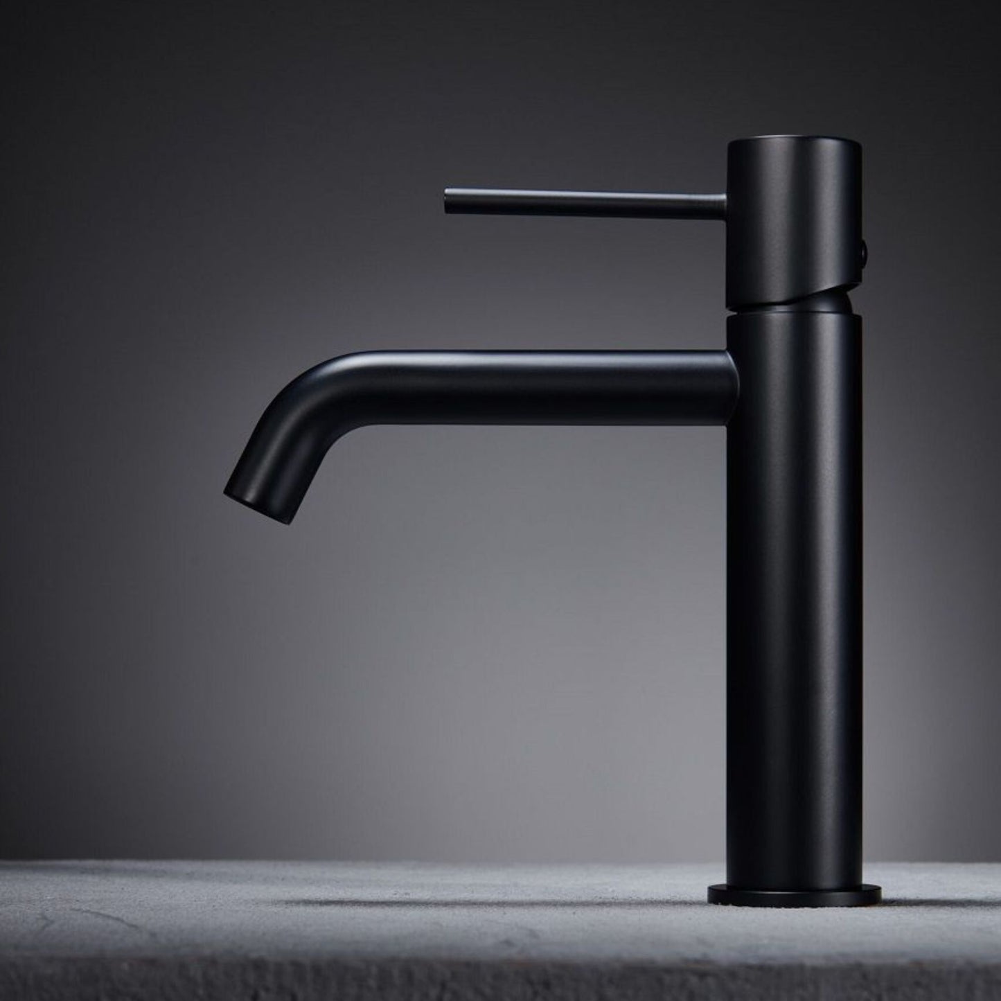 Torneira de lavatório Monza preto mate com design moderno, pousada numa bancada cinza.